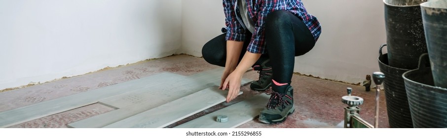 Crouched female bricklayer placing tiles to install a floor