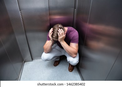Crouched Worried Man With Hands On Head In Elevator