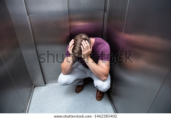 Crouched\
Worried Man With Hands On Head In\
Elevator