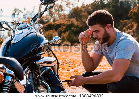 Crouching biker worried about a motorcycle breakdown Сток-фото © 