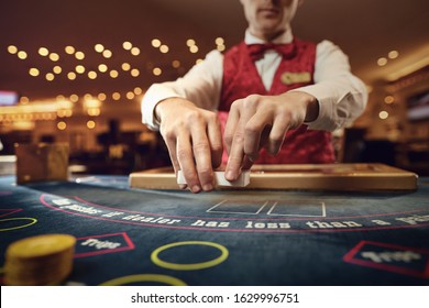 Croupier Holds Poker Cards In His Hands At A Table In A Casino.