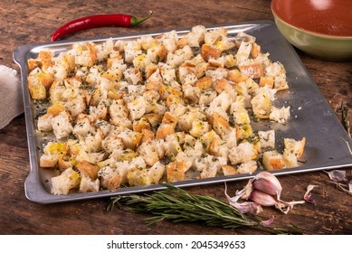 Croutons preparation - diced ciabatta on a baking sheet with olive oil, rosemary and garlic