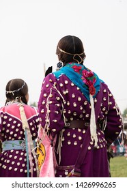 Crow Agency, Montana/USA - August 19, 2018: Native American Woman And Girl In Elk Tooth Dresses With Purple Fabric And  Beaded Headbands At A Pow Wow. Photographed From Behind.