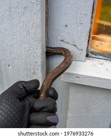 Crowbar Held In Hands While Breaking Down The Wooden Wall Of A Building Being Demolished.