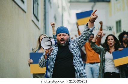 Crowd of activists protesting against Russian military invasion in Ukraine walking in street. - Powered by Shutterstock