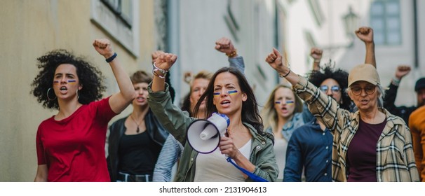 A crowd of activists protesting against the Russian military invasion in Ukraine walking in street. - Powered by Shutterstock