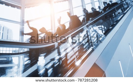 crowd of anonymous blurred business people rushing on a escalator in a business center