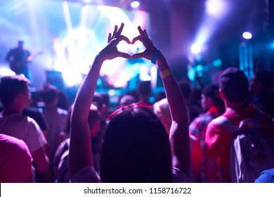 Crowd Of Audience At During A Concert With Silhouette Of A Heart Shaped Hands Shadow
                    