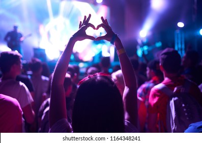 Crowd Of Audience At During A Concert With Silhouette Of A Heart Shaped Hands Shadow.