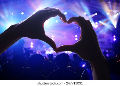 Crowd Of Audience At During A Concert With Silhouette Of A Heart Shaped Hands Shadow