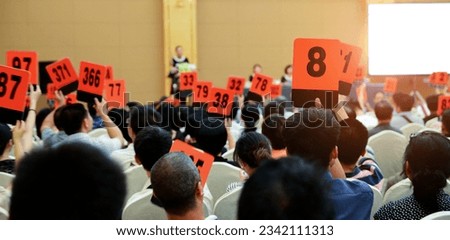 Crowd of bidders holding their numbered bidding paddles at an auction Stockfoto © 
