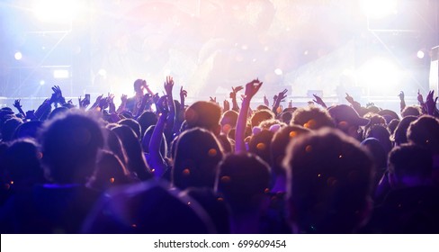 Crowd At Concert - Cheering Crowd In Front Of Bright Colorful Stage Lights