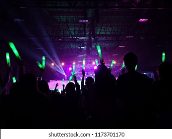 Crowd At Concert : Silhouette People Crowd Happy And Cheering With Led Foam Stick Light In Front Of Bright Colorful Stage Lights, Green Laser Light Beam.