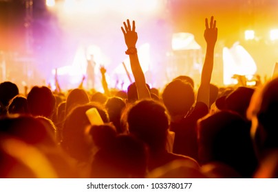 Crowd Of Concert Stage Lights And People Fan Audience Silhouette Raising Hands Or Glow Stick Holding In The Music Festival Rear View With Spotlight Glowing Effect 