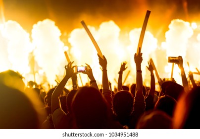 Crowd Of Concert Stage Lights And People Fan Audience Silhouette Raising Hands Or Glow Stick Holding In The Music Festival Rear View With Spotlight Glowing Effect And Smoke