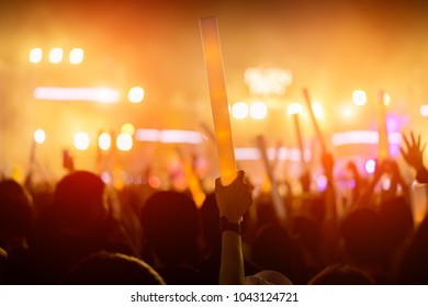 Crowd Of Concert Stage Lights And People Fan Audience Silhouette Raising Hands Or Glow Stick Holding In The Music Festival Rear View With Spotlight Glowing Effect And Smoke