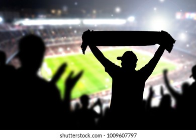 Crowd And Fans In Football Stadium. People In Soccer Game. Person Celebrating Goal And Holding Merchandise Scarf For Favourite Club And Team In Match. Happy Live Sport Silhouette Audience Cheering.