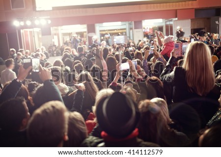 Crowd and fans taking photographs on mobile phones at a red carpet film premiere