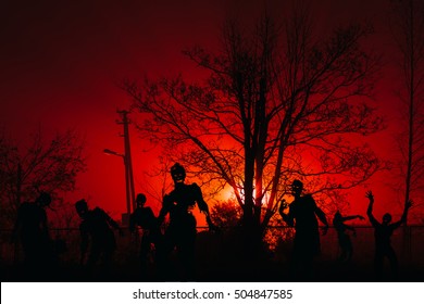 Crowd Of Hungry Zombies In The Woods. Silhouettes Of Scary Zombies Walking In The Forest At Night