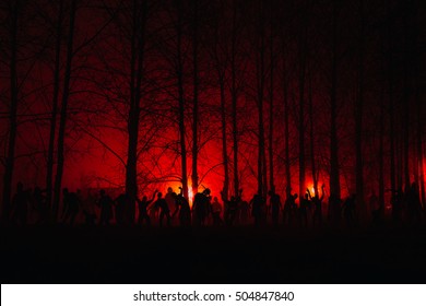 crowd of hungry zombies in the woods. Silhouettes of scary zombies walking in the forest at night. red alert