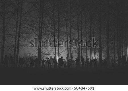 crowd of hungry zombies in the woods. Silhouettes of scary zombies walking in the forest at night. Black and white version