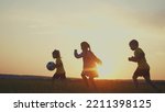 crowd of kids run. people in the park. happy family kid dream concept. brother sister little children holding a ball silhouette run across the field at sunset. happy family kids fun