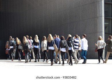 A Crowd Moving Against A Background Of A Gray Wall.