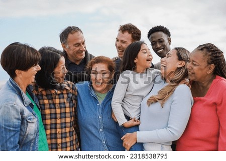 Crowd of multi generational people hugging each other outdoor - Multiracial friends having fun together