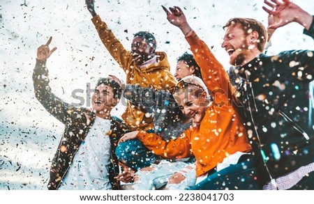 Crowd of multiracial people celebrating success and victory throwing confetti in the air - Football fan cheering soccer team - Party, new year, sport, event and competition concept