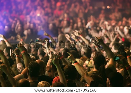 Crowd at a music concert, audience raising hands up