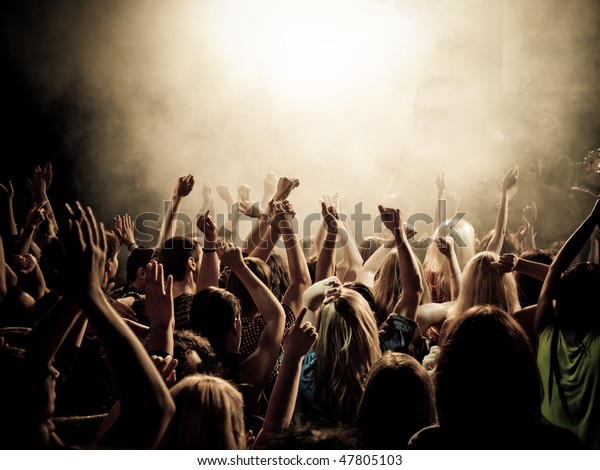 Crowd at a\
music concert, audience raising hands\
up