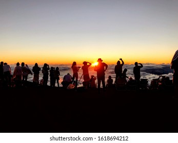 Crowd overlooking a sunset over a cloud seas