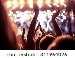 A crowd of people celebrating and partying with their hands in the air to an awesome Dj. High ISO grainy image.