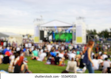A Crowd Of People At A Concert In The Park. Near The Scene. Blurred Background