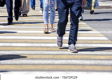crowd of people crossing a street in the city on sunny summer day