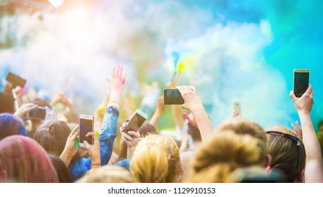 Crowd Of People Dancing And Celebrating Holi Festival Of Colors. People Taking Photos With Mobile Phones At Color Festival