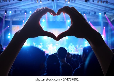 Crowd Of People At During A Concert  With A Heart Shaped Hand Shadow