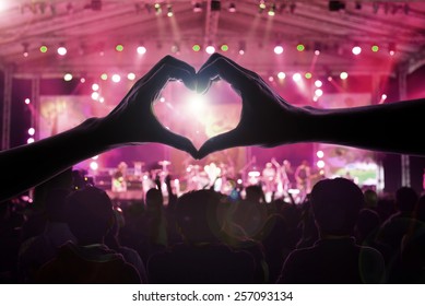 A Crowd Of People At During A Concert With A Heart Shaped Hand Shadow Male And Female