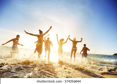 Crowd of people or friends runs to sunset sea. Beach holidays travel concept - Shutterstock ID 574356844