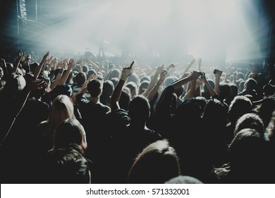  Crowd Of People Silhouettes With Their Hands Up During The Concert. Dark Background, Smoke, Concert  Spotlights