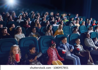 Crowd of people sitting in comfortable seats in modern movie theatre. Children, teens, adults watching  film and sipping fizzy drinks. Concept of cinematography and entertainment. - Powered by Shutterstock