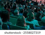 Crowd of people sitting and listening during a seminar or conference in indoor venue.