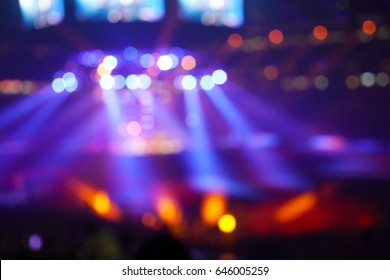 Crowd Of People In A Stadium Watching A Popular Rock Music Concert With Spotlights, Screens And Glowing Lights.