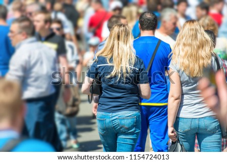 Crowd of people walking on city street with young woman with long hair in centre