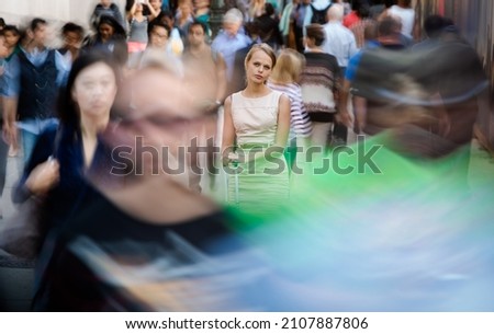 Crowd of people walking on city street - motion blurred image with unrecognizable faces - Young woman standing still, feeling down, depressed Stockfoto © 