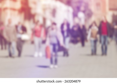 Crowd of People Walking On the Street in Bokeh, unrecognizable group of men and women with shopping bags as blur urban background