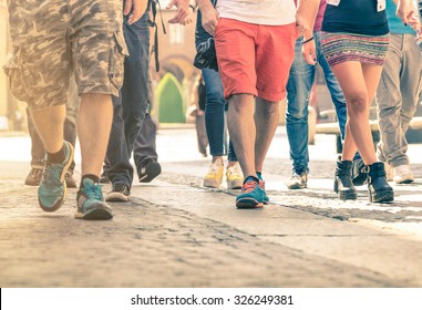 Crowd Of People Walking On The Street - Detail Of Legs And Shoes Moving On Sidewalk In City Center - Travelers With Multicolor Clothes On Vintage Filter - Shallow Depth Of Field With Sunflare Filter