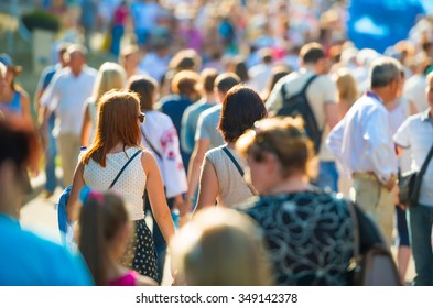 Crowd of people walking on the sunny and busy city street. Soft focus