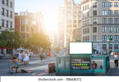 Crowd Of People Walking In Union Square Park Near The 14th Street Subway Station In Manhattan, New York City NYC With A Blank Billboard Sign And Glowing Sunlight In The Background