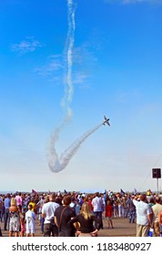 A Crowd Of People Watching Aerobatics During The Airshow
